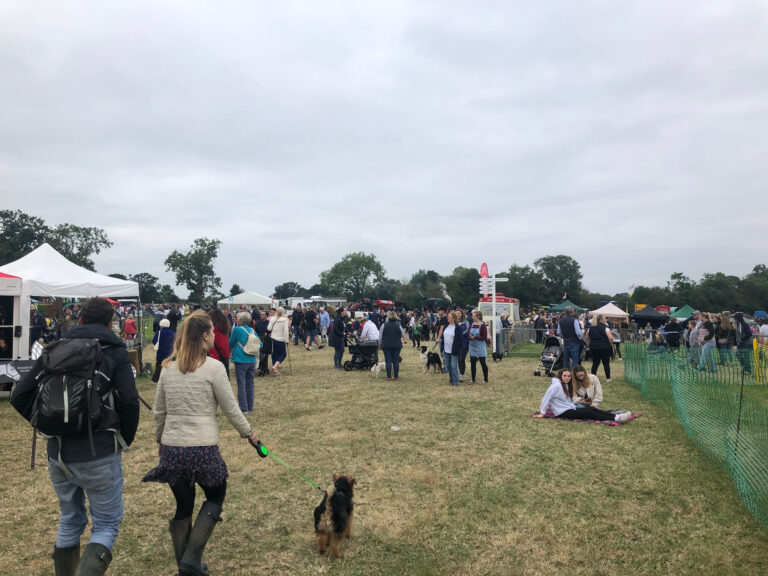 Photo of visitors enjoying outdoor countryside show, with marquees, display rings and people with their dogs
