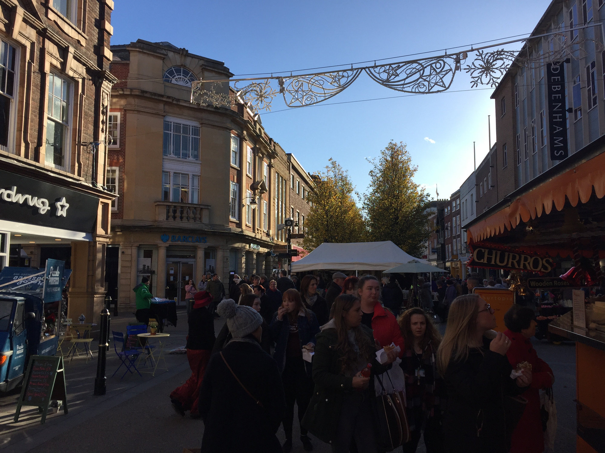 Visitors on high street at Christmas market looking at stalls and enjoying food