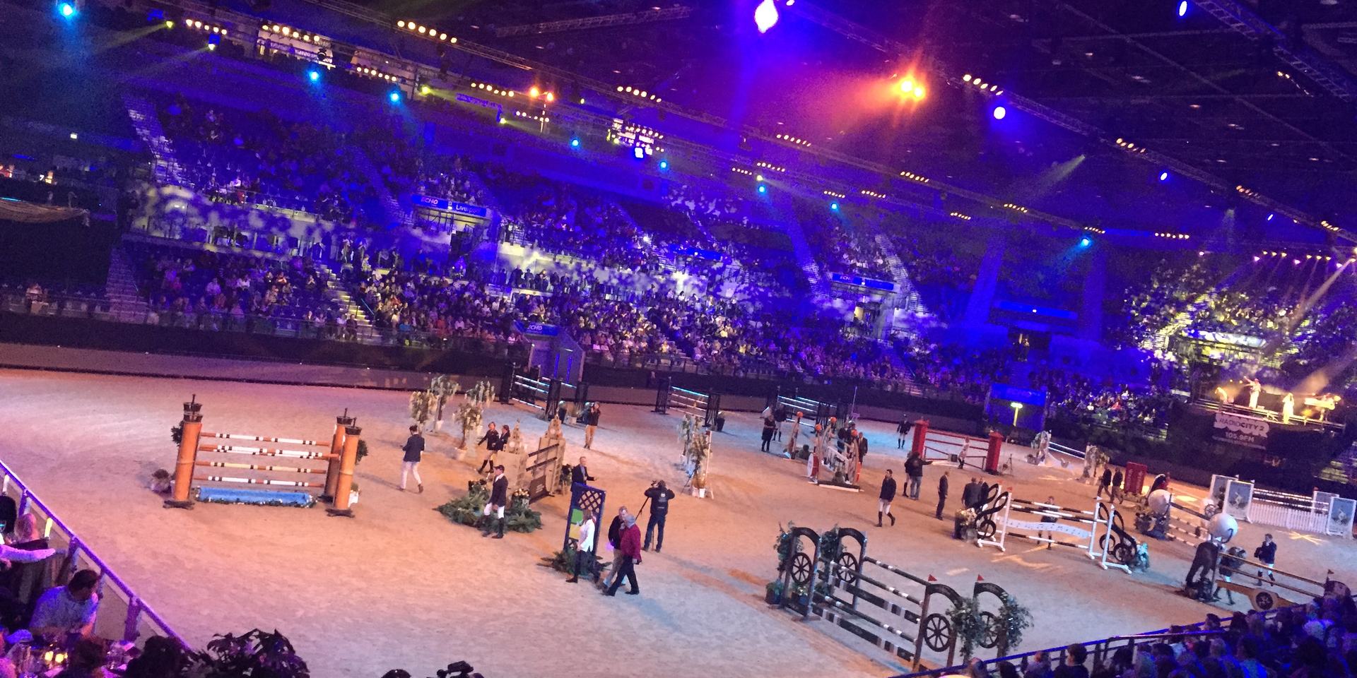 Indoor show-jumping arena lit up for an evening performance